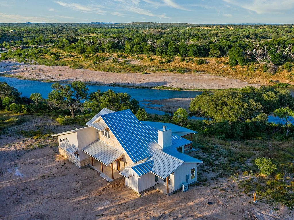Mas-O-Llano house with a blue roof, overlooking a river near Austin and Dallas, TX